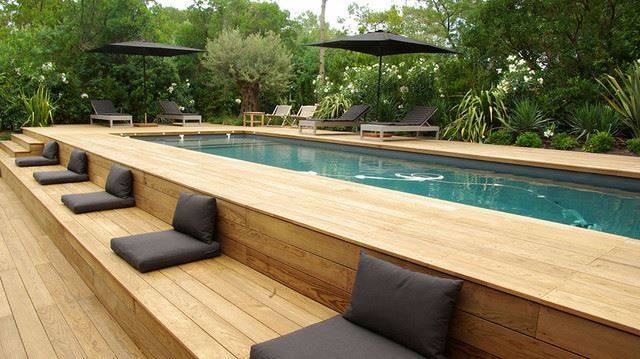 wood panel above ground lap pool with black cushions and umbrellas