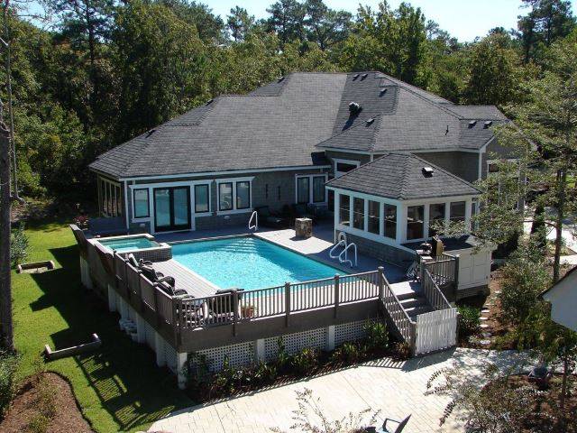 large rectangle pool with deck around it at back of house