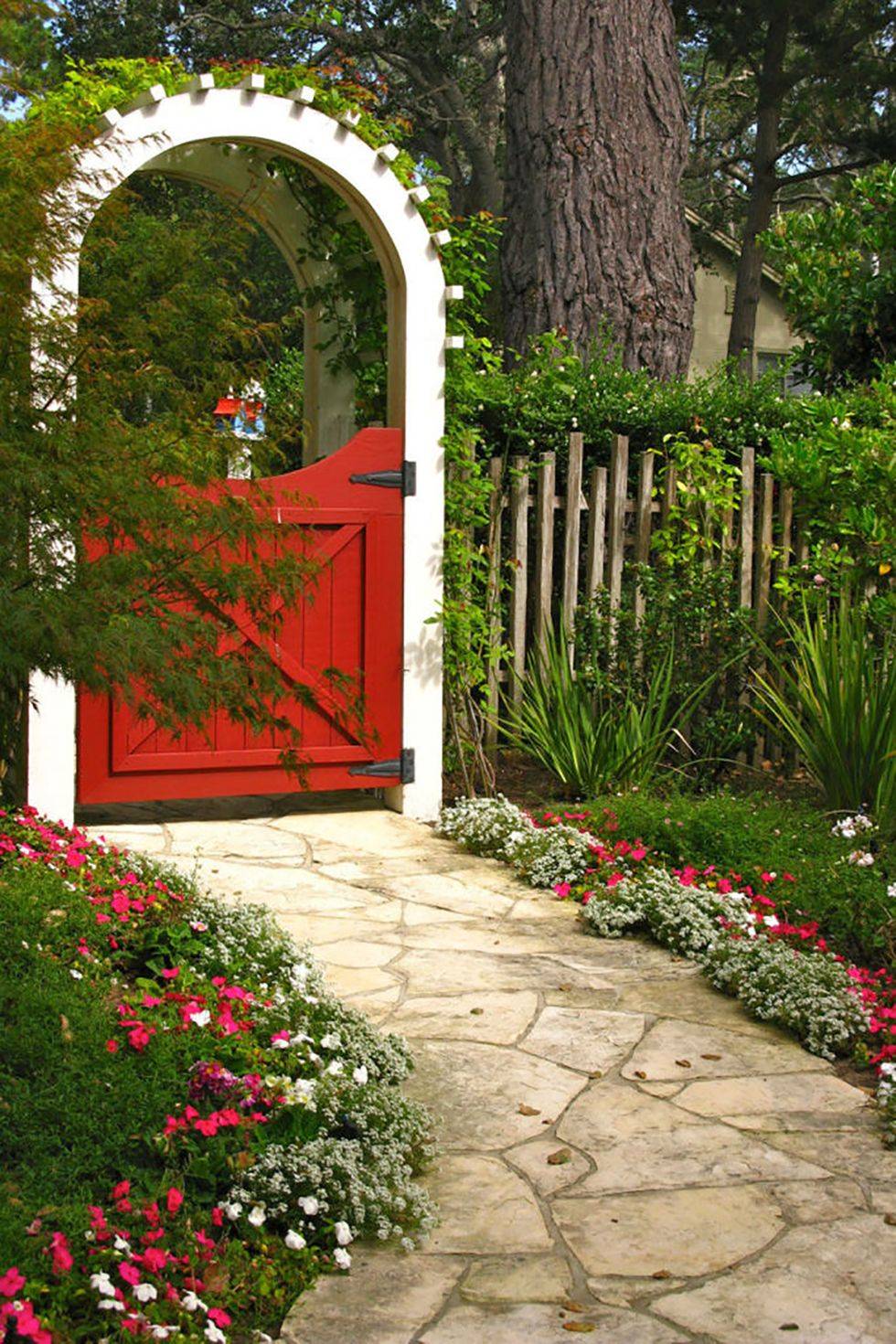 little red garden gate door with with arbor covered in moss