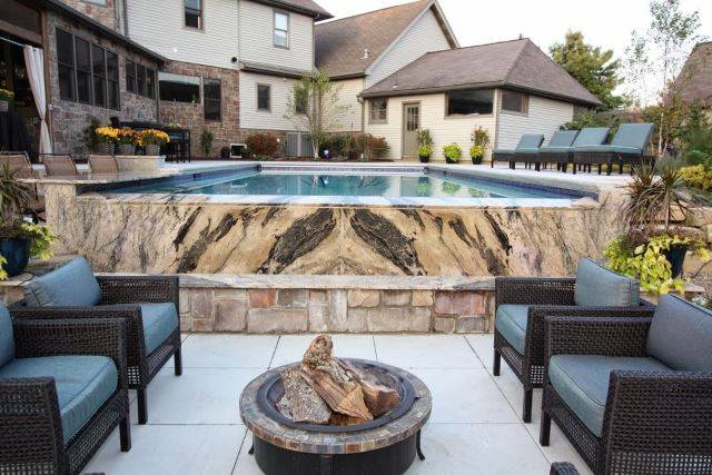 modern marble above ground pool with seating area and fire pit