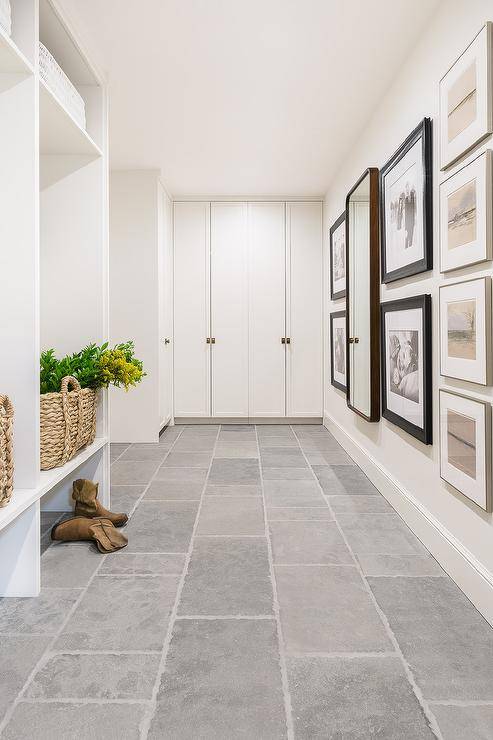 modern mudroom with individual white lockers with brown woven baskets, wall of white closets and wall of art making up the collage wall.