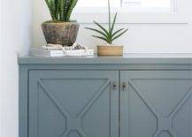 Hallway nook cabinet with blue x mullion trim features a decorative appeal topped with a matching blue countertop and finished with lovely succulents.