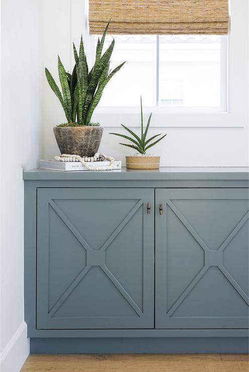 Hallway nook cabinet with blue x mullion trim features a decorative appeal topped with a matching blue countertop and finished with lovely succulents.