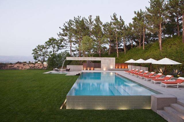 large above ground infinity pool with ocean view white umbrellas on grass