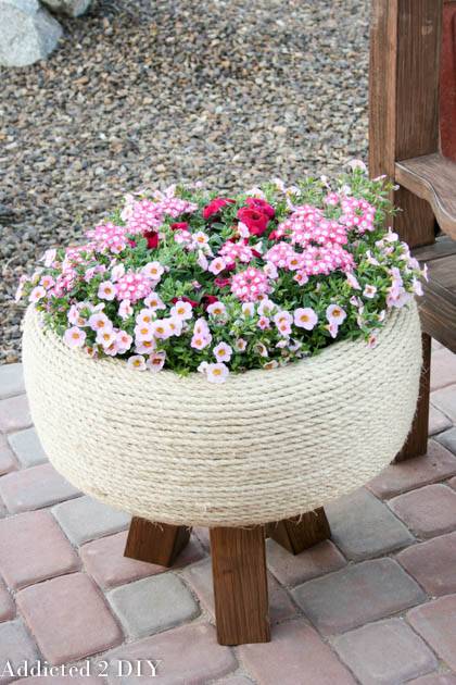 jute wrapped tire planter with spring flowers on patio