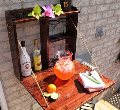 outdoor bar flip down mounted to brick wall with drinks and flowers