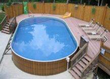 oval wood frame pool with deck built on one side on cement slab with lounge chairs on deck