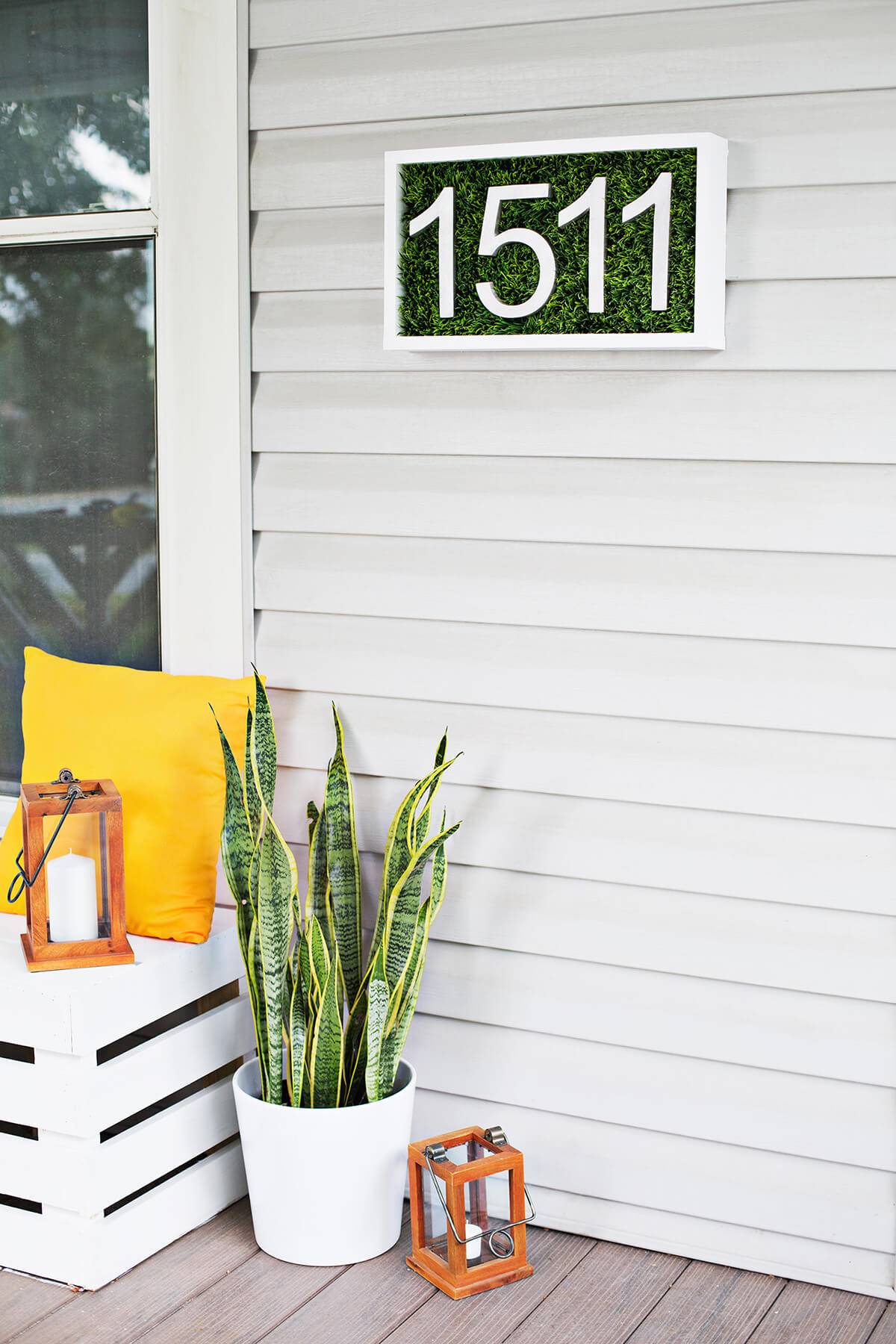 patch of grass house number sign on white siding with yellow pillow snake plant lanterns