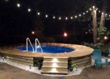 above ground pool oval shape with deck built around it at night with string lights