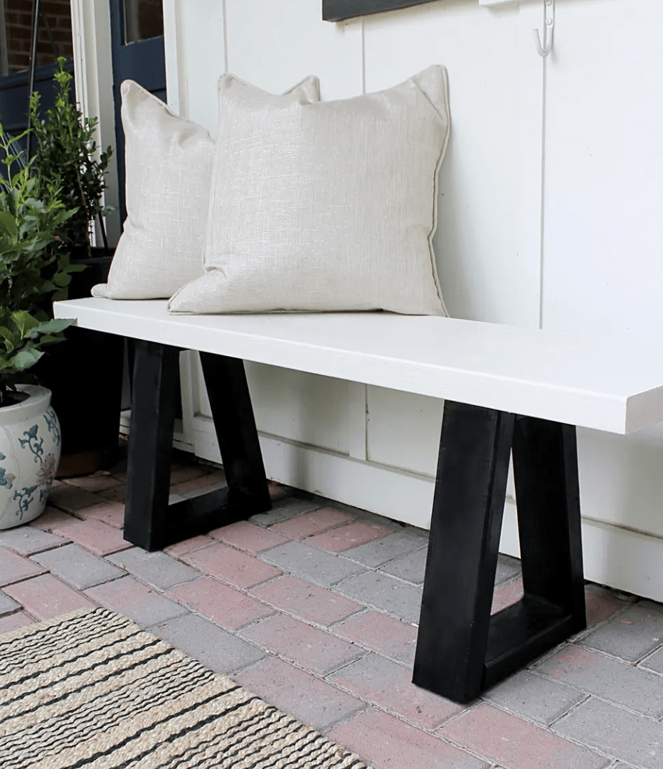 close up of white and black bench outside with two white pillows