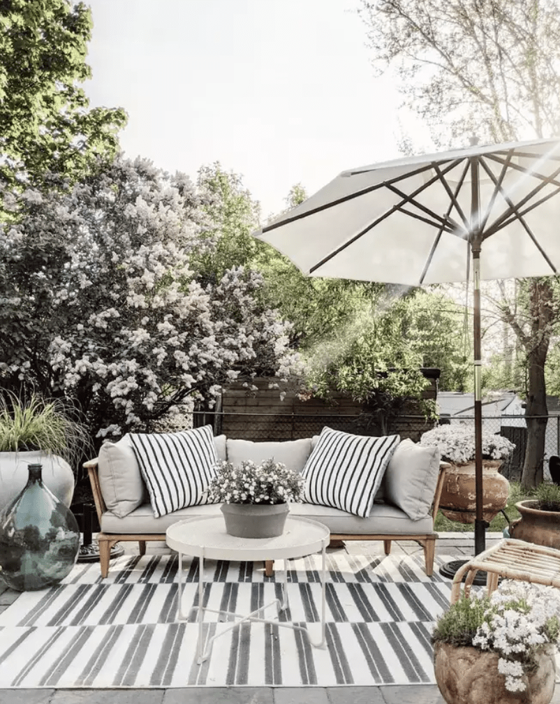 outdoor patio with black and white strip rug umbrella and outdoor couch