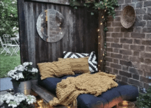 napping nook in backyard made out of pallets along fence and brick wall