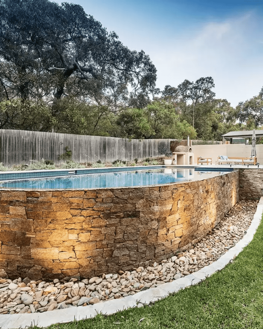 above ground pool with stone brick work wall and stones around the ground