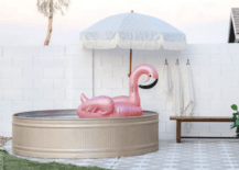 stock tank pool with umbrella and inflatable pink flamingo