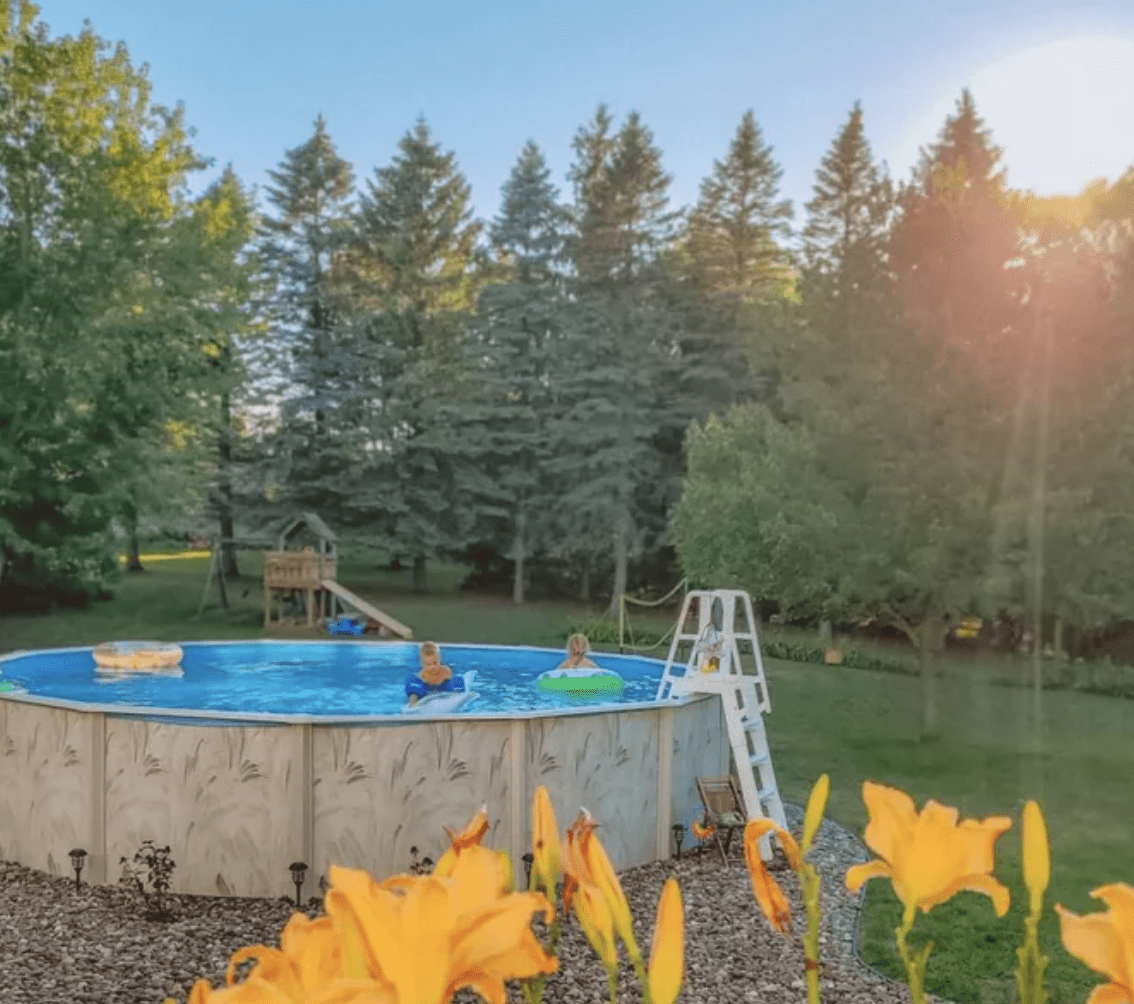 above ground pool with ladder in country surrounded by trees and forest
