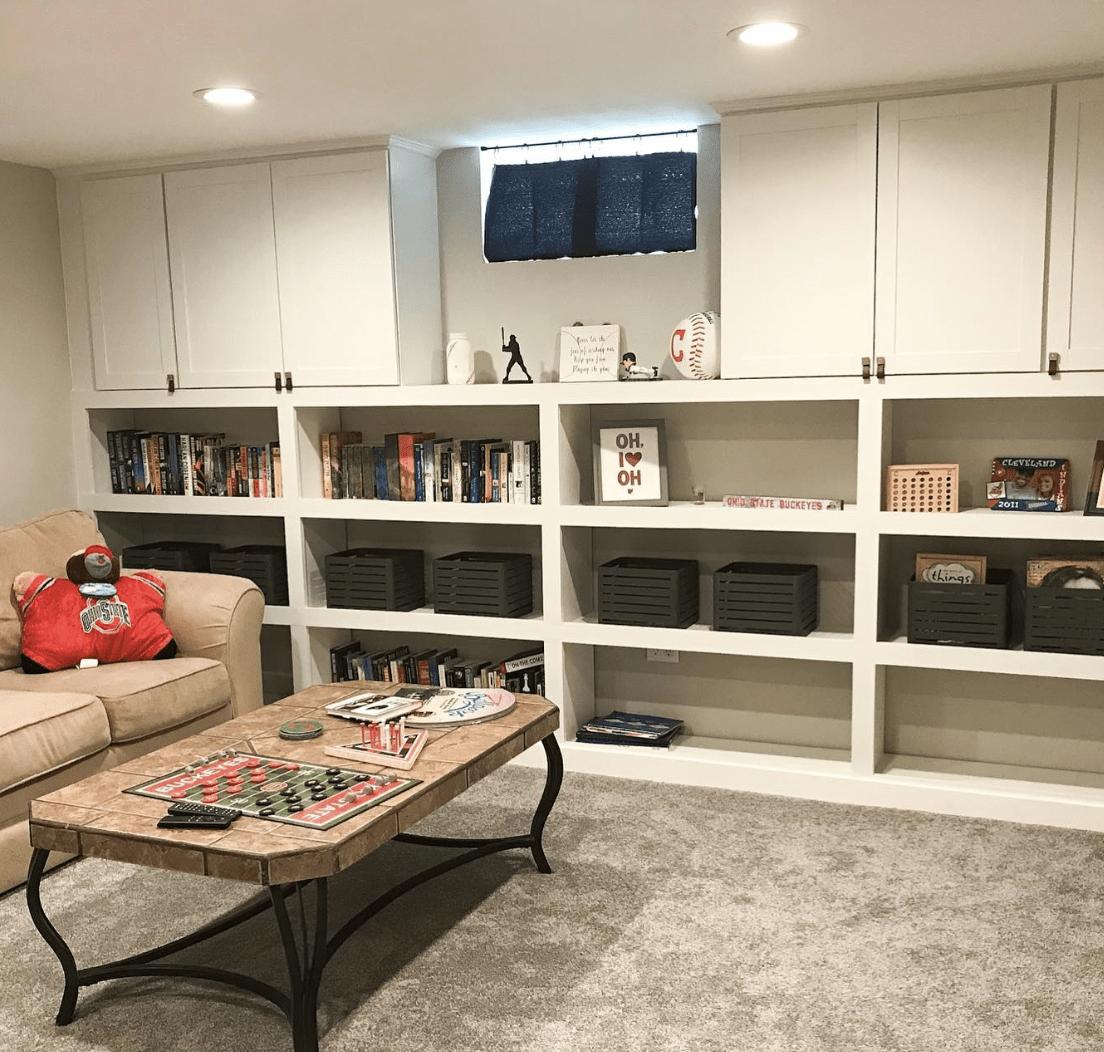 white built in storage in basement with couch and coffee table baskets on shelves