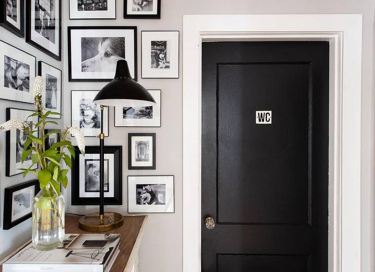 Small entryway features a black and white photo wall on the wall bringing life to a small foyer space. White trim around a black water closet door adds a contrasting finish near the small entry space.
