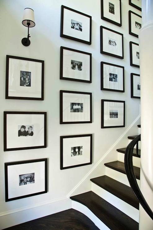 Stunning staircase featuring black and white family photo wall with Thomas O'Brien Vendome Single Sconce in Oil Rubbed Bronze.