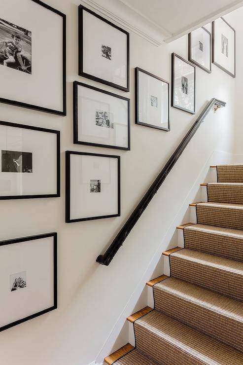 Gallery wall art staggered along a staircase wall in black frames showcasing black and white lifestyle photos.