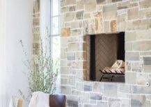 Cottage dining area is warmed by a gray stone fireplace fitted over a firewood nook.