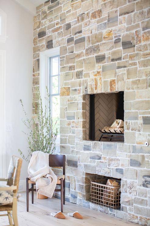 Cottage dining area is warmed by a gray stone fireplace fitted over a firewood nook.