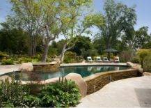 stone wall above ground pool with hot tub built in