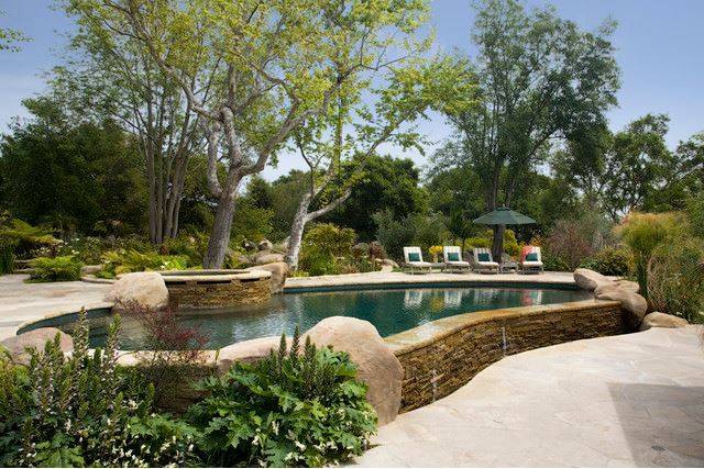 stone wall above ground pool with hot tub built in