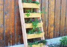 tiered ladder leaning on fence with plants inside