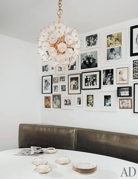 Amazing banquette style dining space with eclectic photo wall gallery, gray metallic leather banquette, oval dining table and brass chandelier.