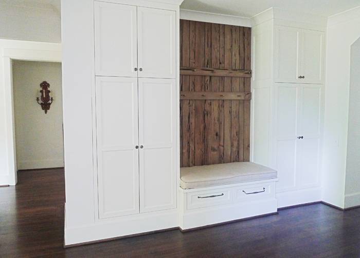 Fabulous mud room area with floor to ceiling shaker closets flanking a built-in storage bench with pecky cypress paneled back wall adorned with peg coat hooks.