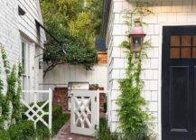 Red brick herringbone pavers lead past a beautiful garden to a white chippendale gate.