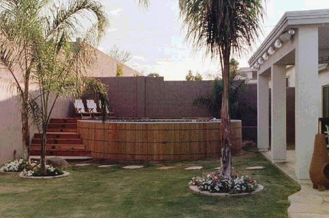 wood framed pool on grass above ground palm tree