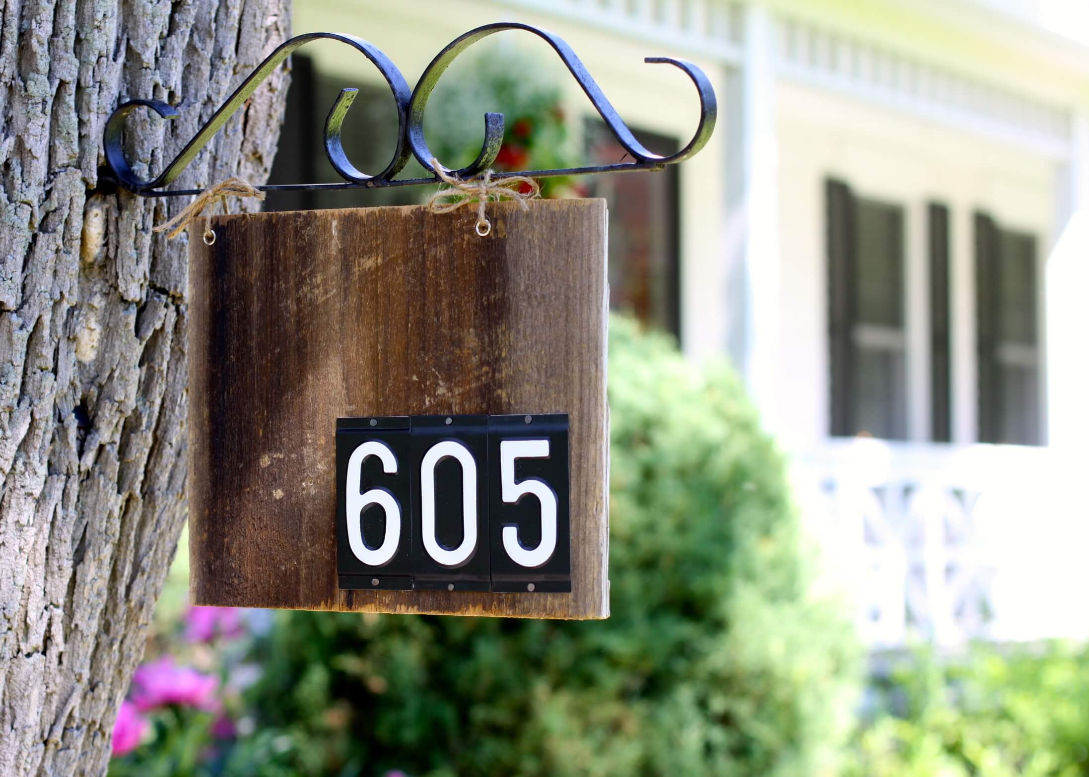 wood sign hanging from tree house numbers