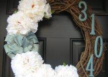 close up of wreath on front door with house numbers and white flowers blue ribbon