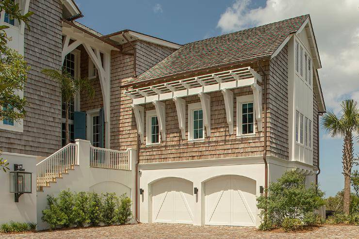 Brown shingle house features a double garage and blue shutters.