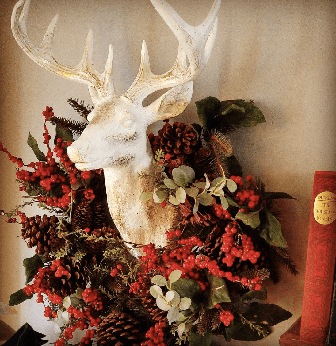 red berry pinecone wreath hanging around a white deer head