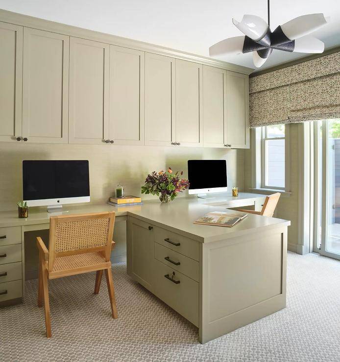 Shared tan and green home office features olive green cabinetry with oil rubbed bronze hexagon knobs and cane desk chairs.