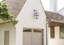House features a white brick garage with gray chevron door lit by a carriage lantern.