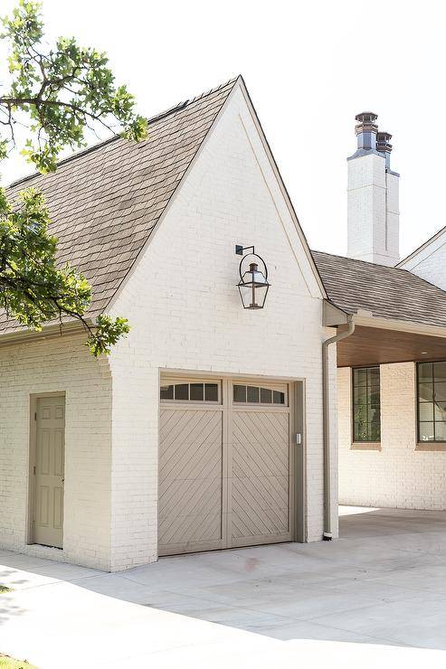 House features a white brick garage with gray chevron door lit by a carriage lantern.