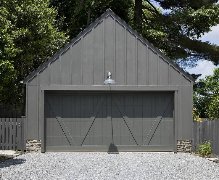 A stone and black wood garage is fitted with black dual garage doors.