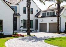 White beach house features gray brick winding driveway that leads to a 2-car attached brown garage.