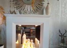 a faux white fireplace with a mirror screen and pillar candles, a sunburst mirror, vases on the mantel for decor