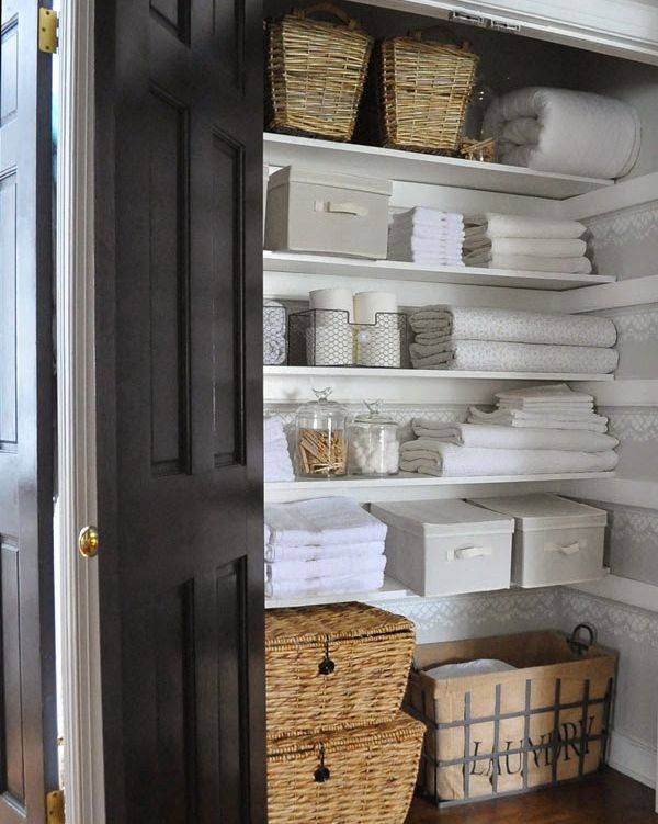 organized linen bathroom closet with folded towels and linens weaved baskets and totes