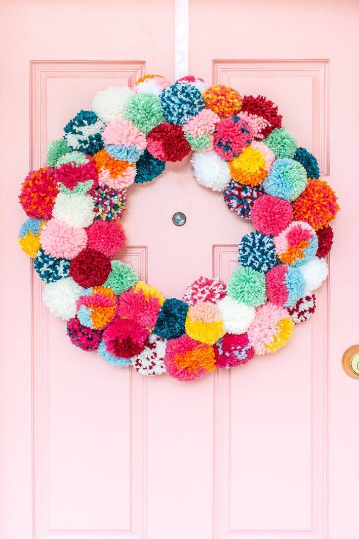 colorful pom pom wreath on pink door