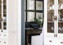 Cottage style home office with gray pocket doors features a brown farmhouse desk with white slipper chair.