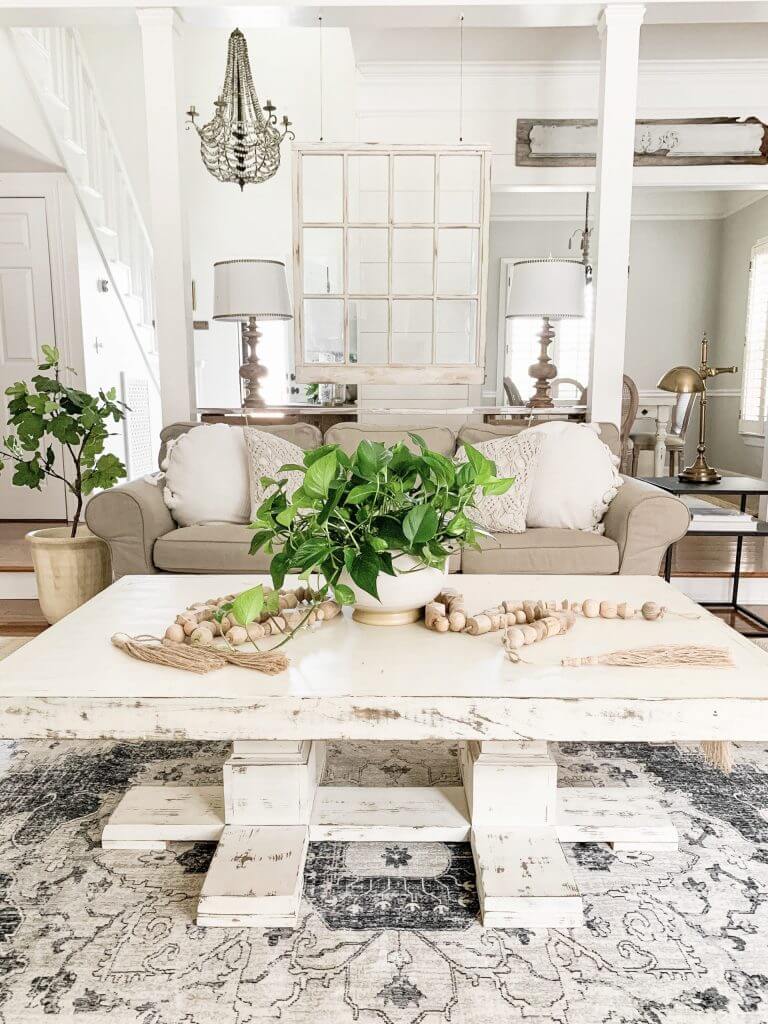 white country chic living room with large wood rustic coffee table white beige sofa hanging distressed rustic window chandelier white pillars wooden beaded decor accents