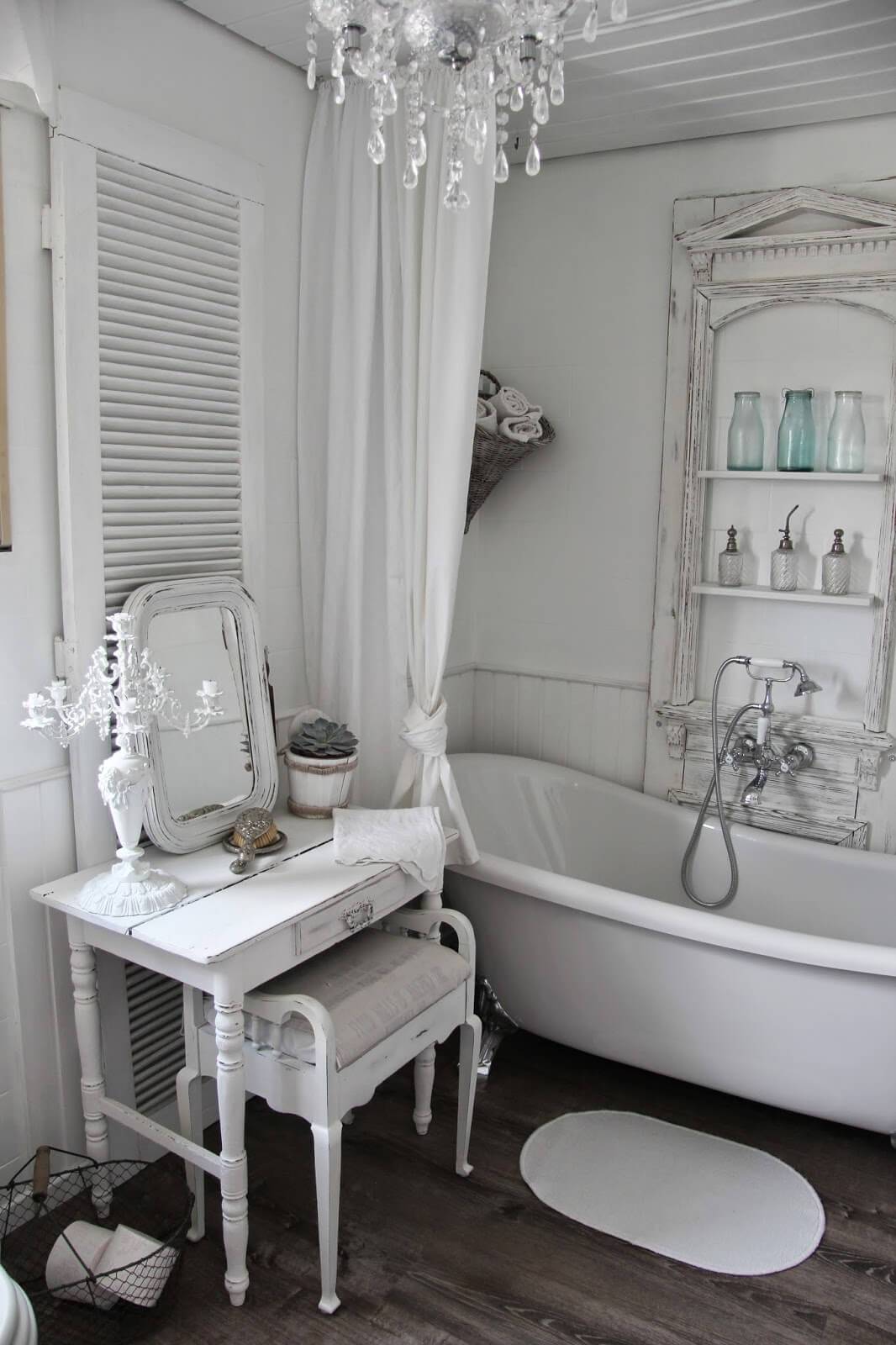 clawfoot antique tub in country chic bathroom with white shutter chandelier crystal vanity with mirror and old architecture turned shelving