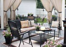 white pergola with curtains seating area with black patio chairs and outdoor rug