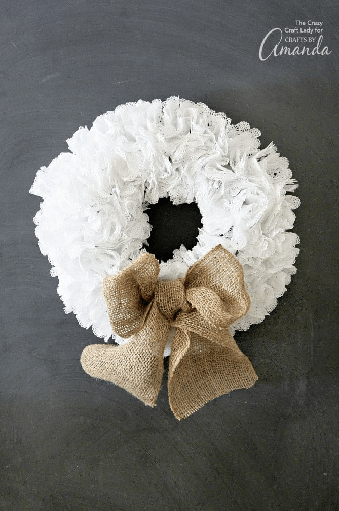 white doily wreath on black background with burlap bow ribbon