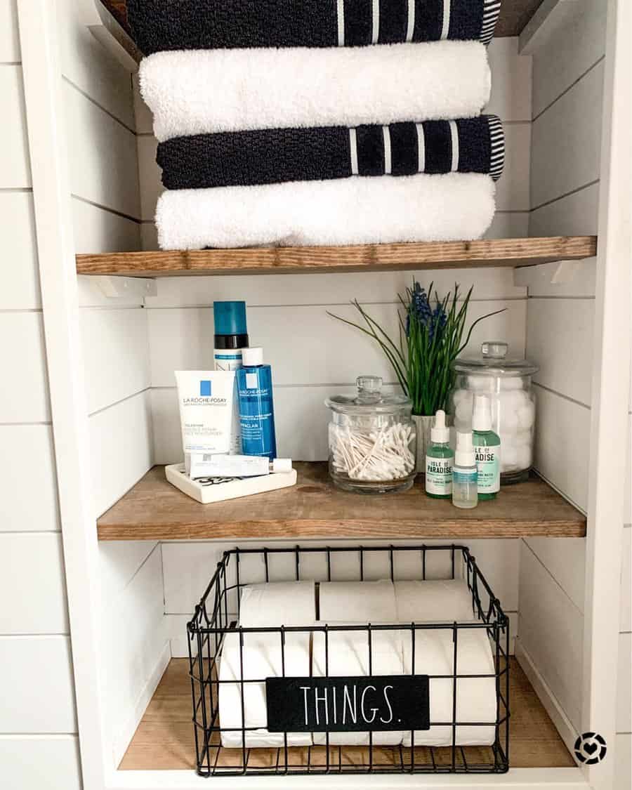 Close up of farmhouse style closet with folded black and white towels toiletries and wire basket